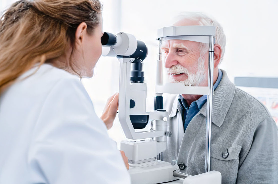 An elderly man is undergoing an eye exam by an eye doctor.