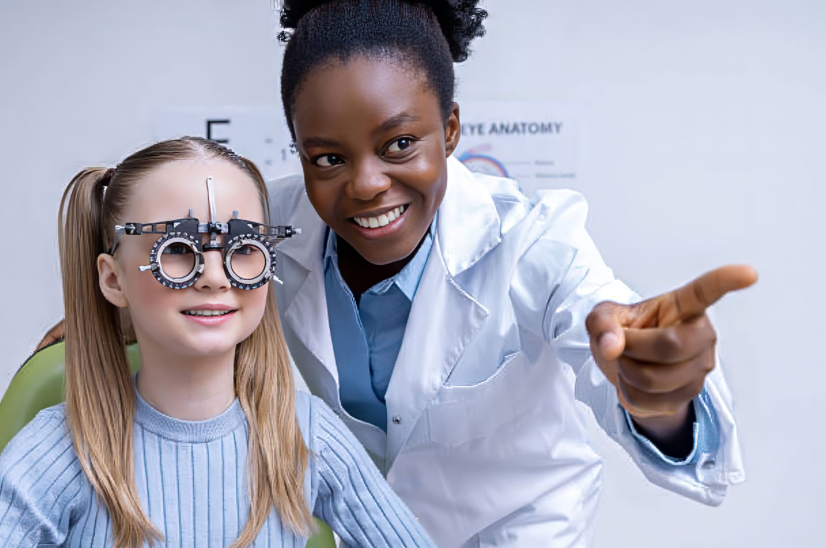 An African American eye doctor is performing an eye exam on a Caucasian girl.